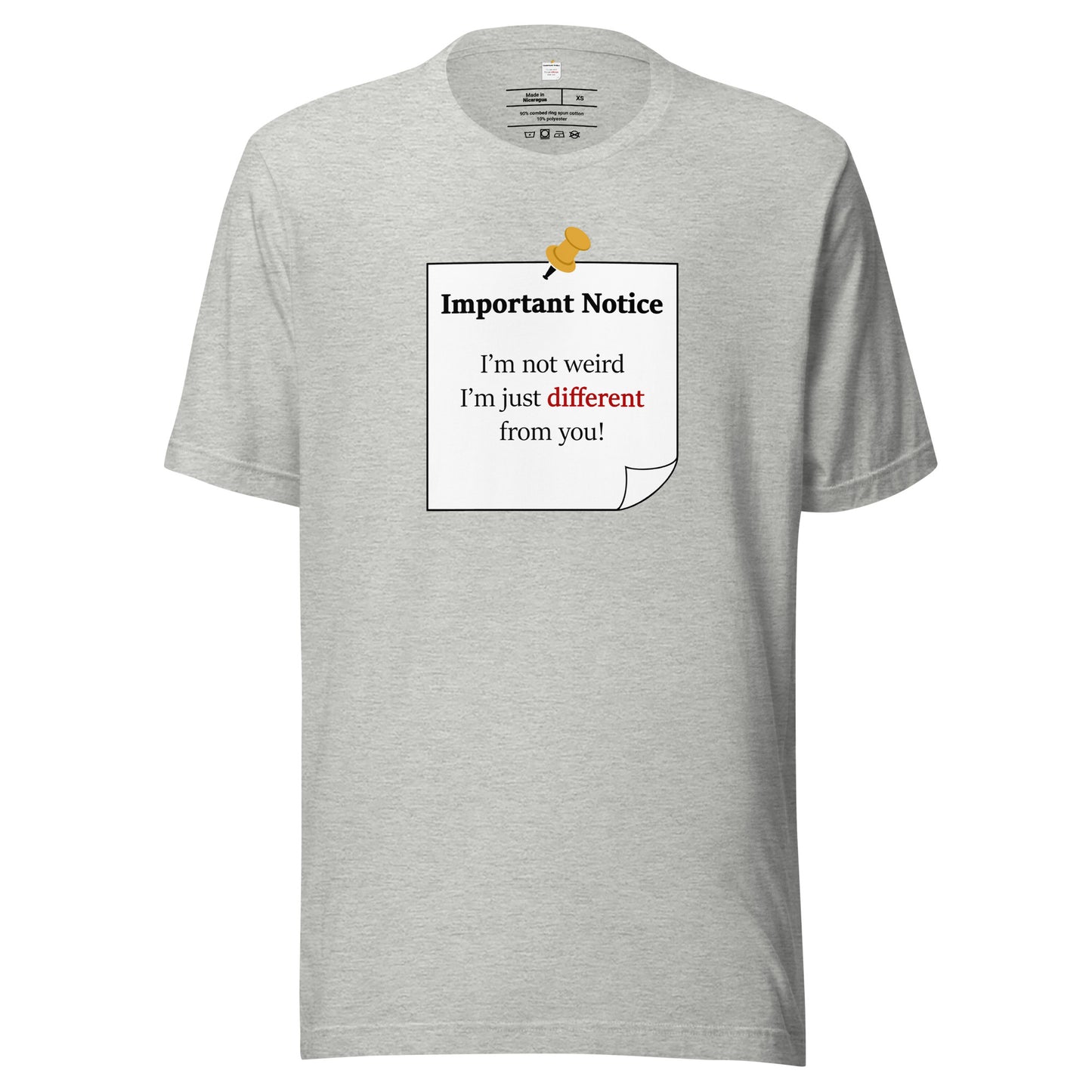A unisex athletic-heather grey classic cotton t-shirt, featuring a printed black-outlined square note with a white background and a yellow pushpin at the top centre. The note displays the slogan: "Important notice: I’m not weird, i'm just different from you! with the word different highlighted in bold red for emphasis.