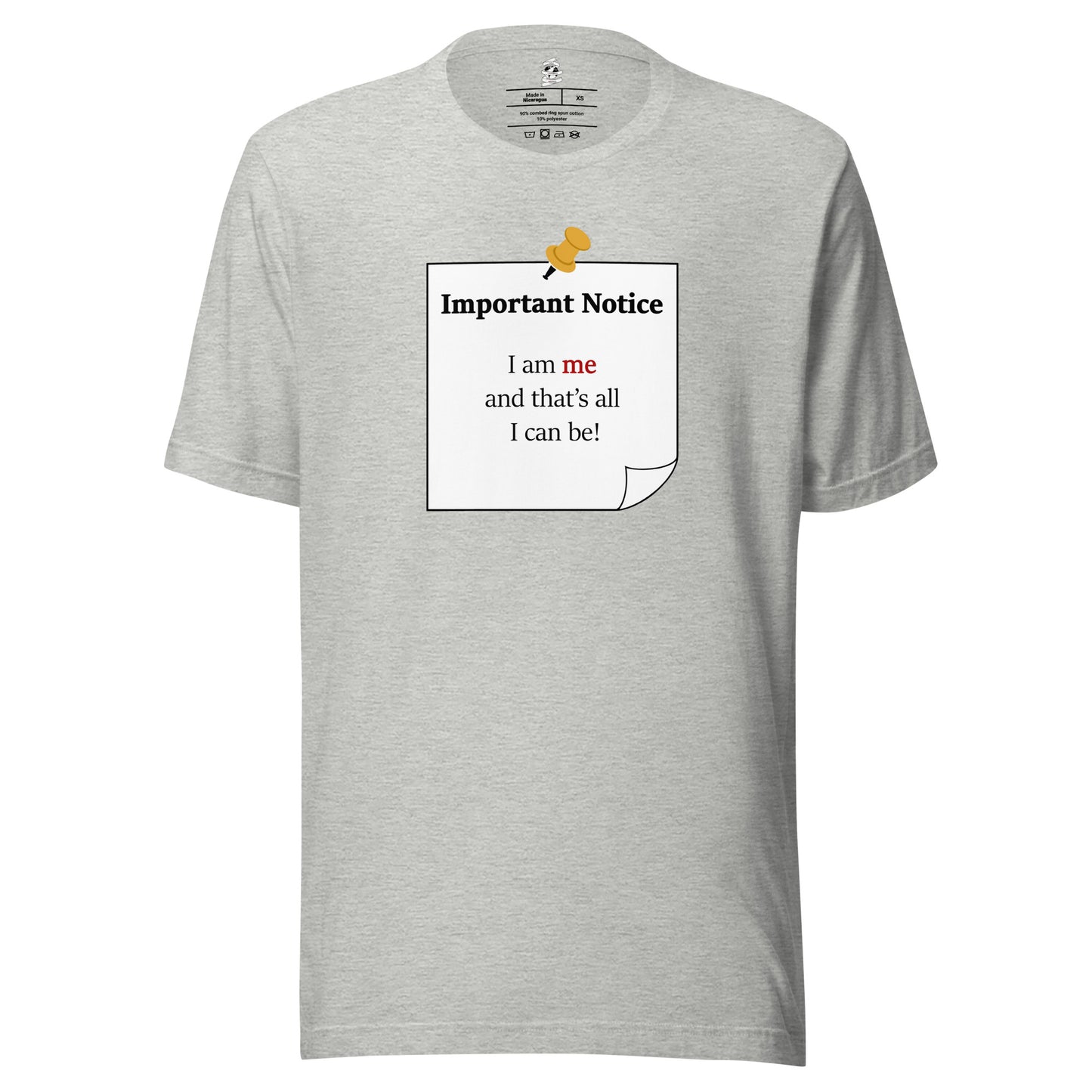 A unisex athletic-heather grey classic cotton t-shirt featuring a printed black-outlined square note with a white background and a yellow pushpin at the top centre. The note displays the slogan: "Important notice: I am me that's all I can be" in black, with the word me highlighted in bold red for emphasis.