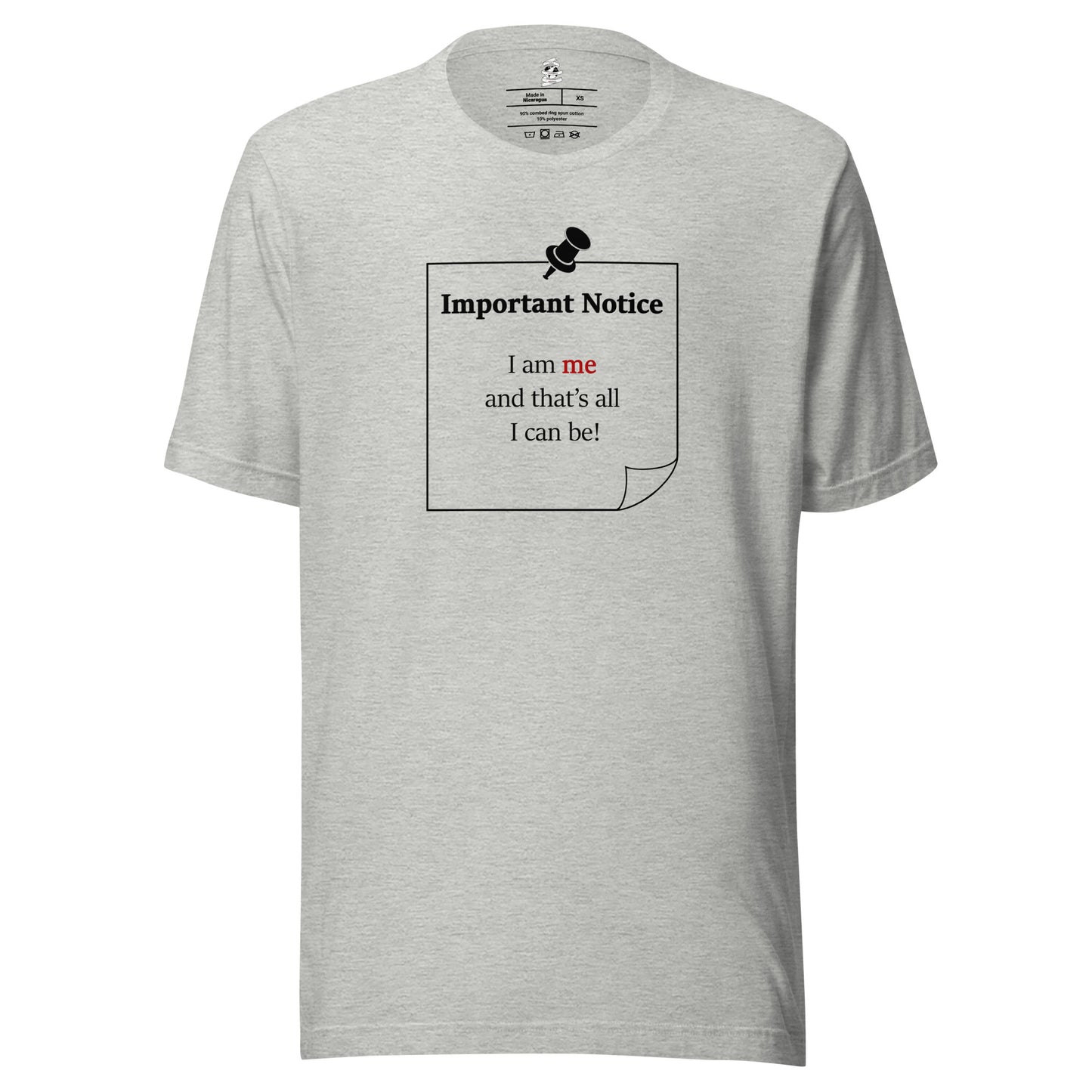 A unisex athletic-heather grey classic cotton t-shirt featuring a printed black-outlined square note and a black pushpin at the top centre. The note displays the slogan: "Important notice: I am me and that's all I can be" in black, with the word me highlighted in bold red for emphasis.