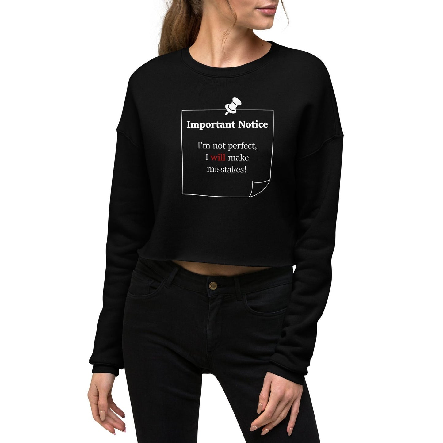 Woman wearing black cropped fleece sweatshirt jumper, showcasing a printed white-outlined square note and a white pushpin at the top centre. The note displays the slogan: "Important notice: I’m not perfect, I will make mistakes" in black, with will in bold red for emphasis.
