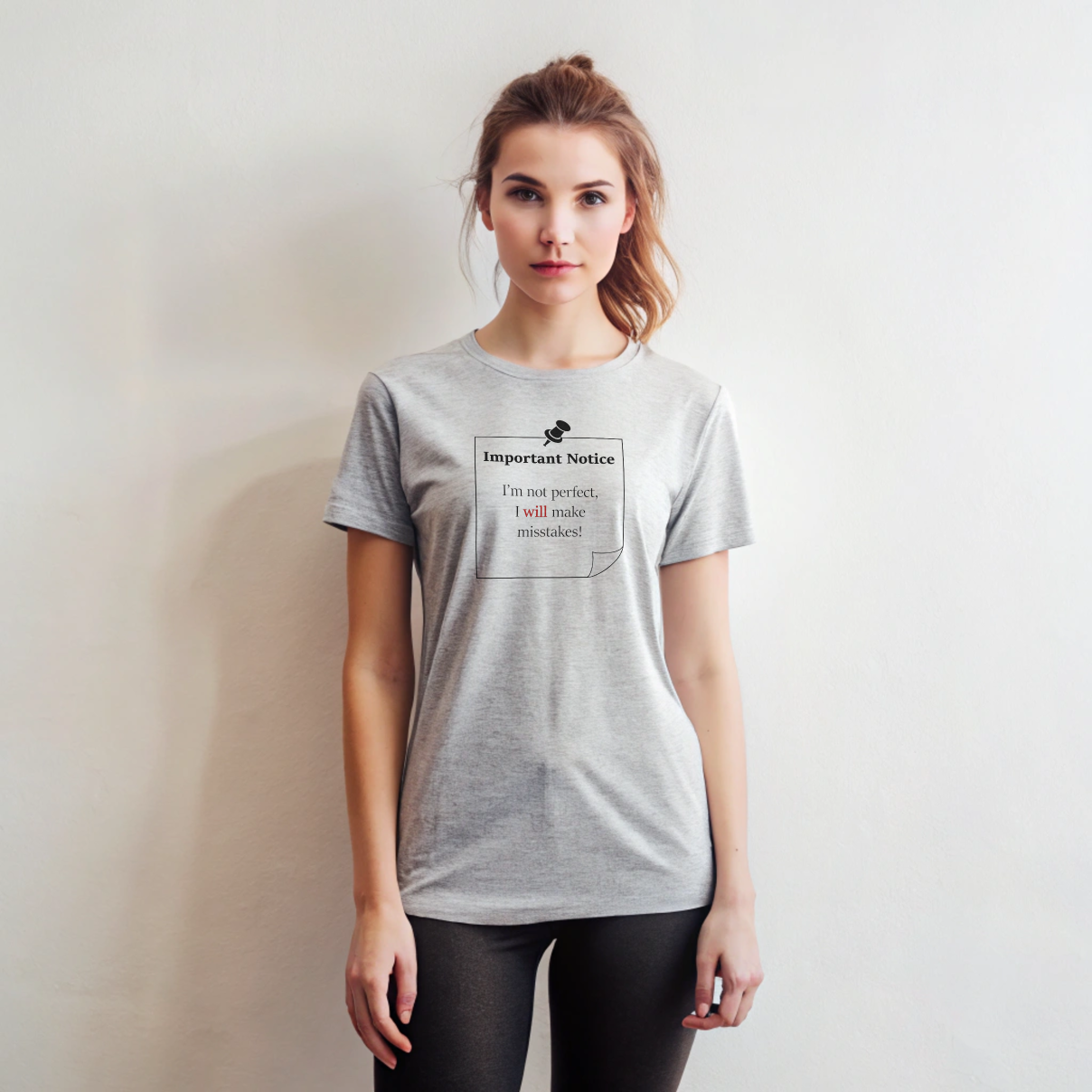 A woman in black leggings wearing a grey classic cotton t-shirt featuring a black-outlined square note with a black push pin. The note displays the slogan: 'Important Notice: I’m not perfect, I will make mistakes,' with 'will' in bold red for emphasis.