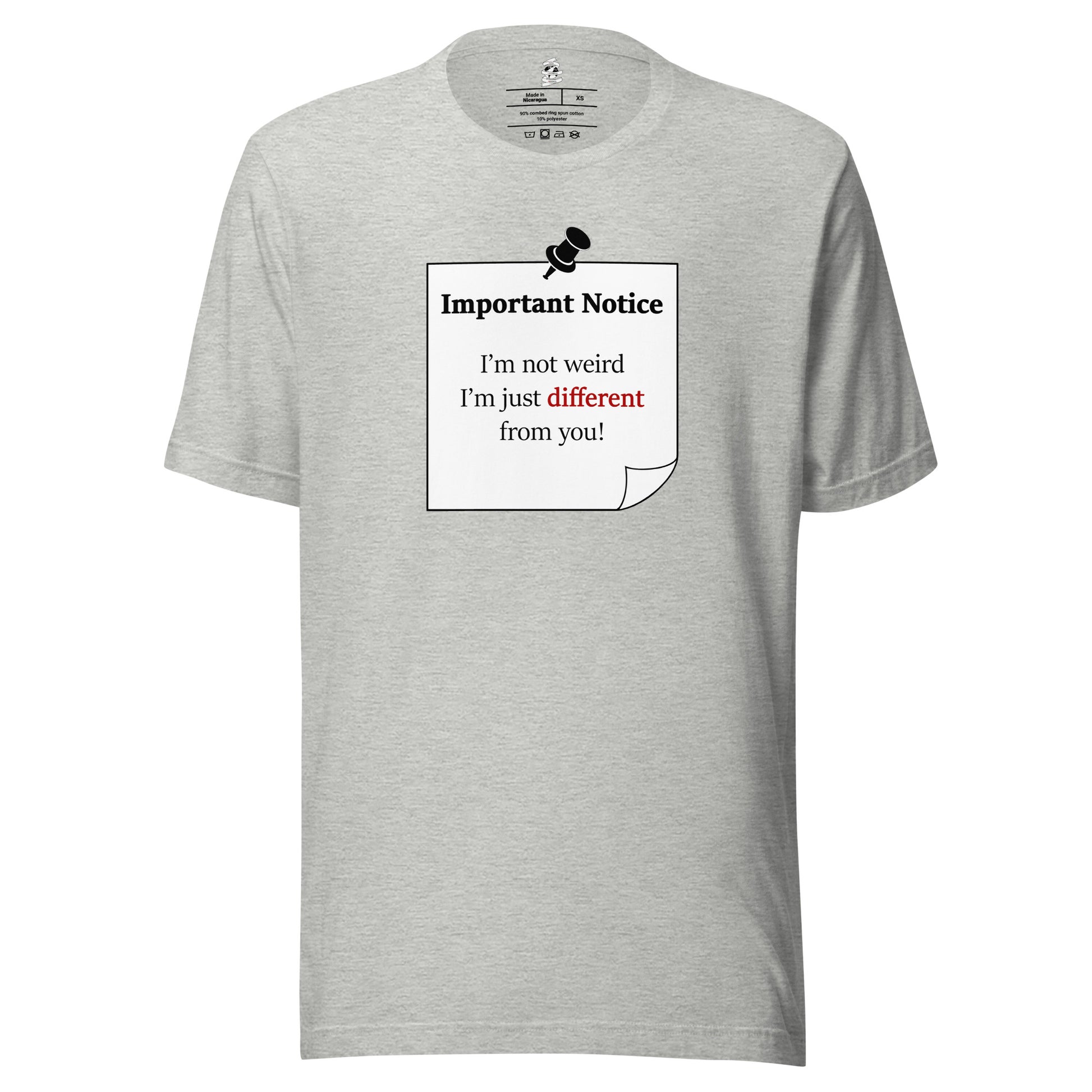 A unisex athletic-heather grey classic cotton t-shirt, featuring a printed black-outlined square note with a white background and a black pushpin at the top centre. The note displays the slogan: "Important notice: I’m not weird, i'm just different from you! with the word different highlighted in bold red for emphasis. 