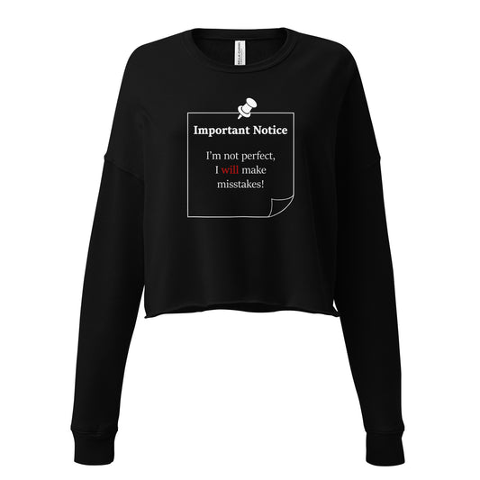 A woman’s black cropped fleece sweatshirt jumper featuring a printed white-outlined square note and a white pushpin at the top centre. The note displays the slogan: "Important notice: I’m not perfect, I will make mistakes" in black, with the word will highlighted in bold red for emphasis.